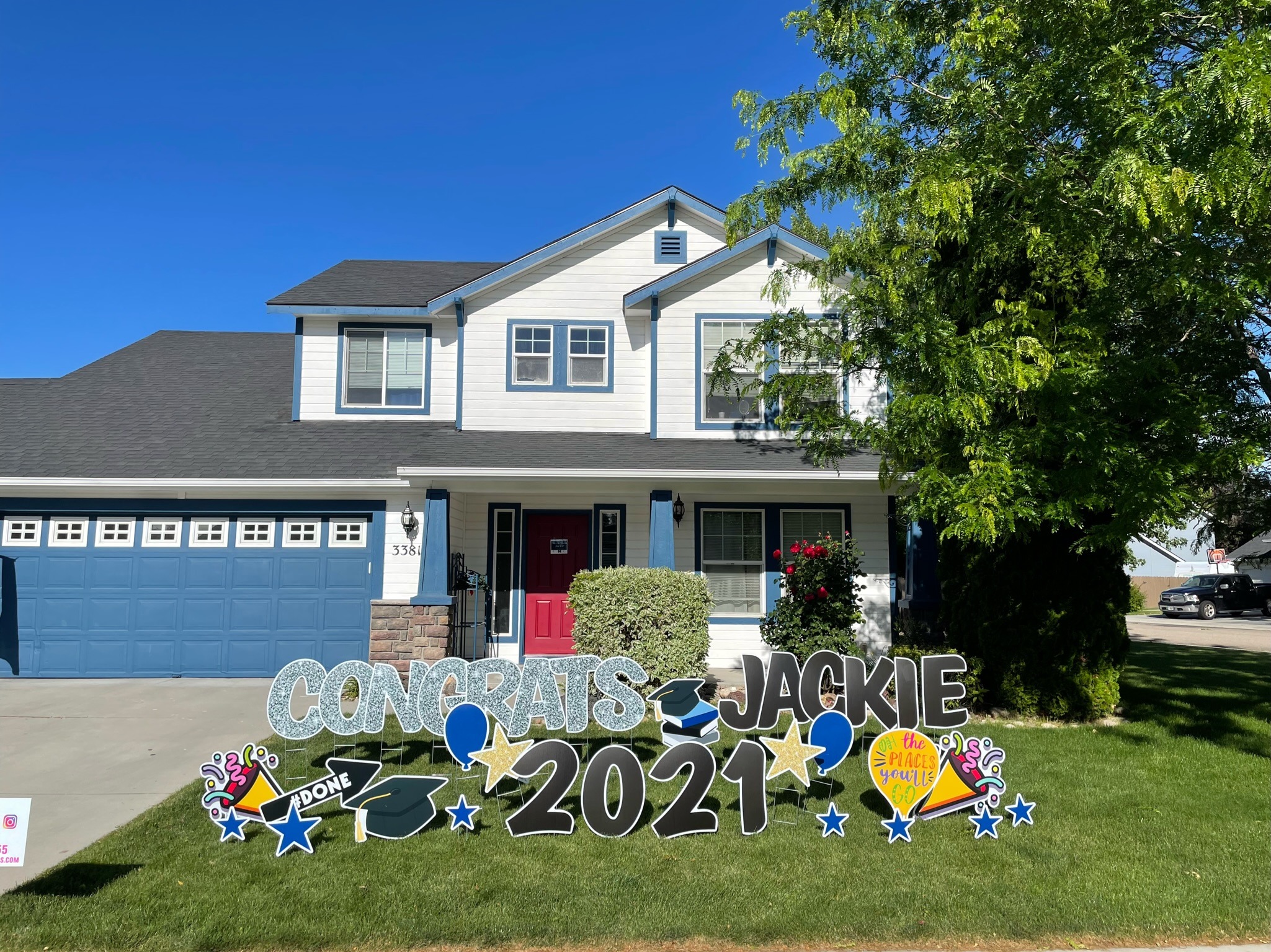 Congrats Jackie 2021 graduation yard card display with colorful letters and stars in front of a blue Boise home