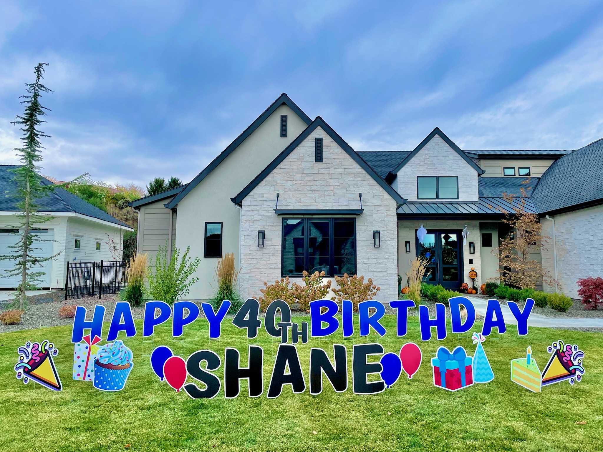 Happy 40th Birthday Shane yard card display with blue and black letters and party art in front of a modern Boise home